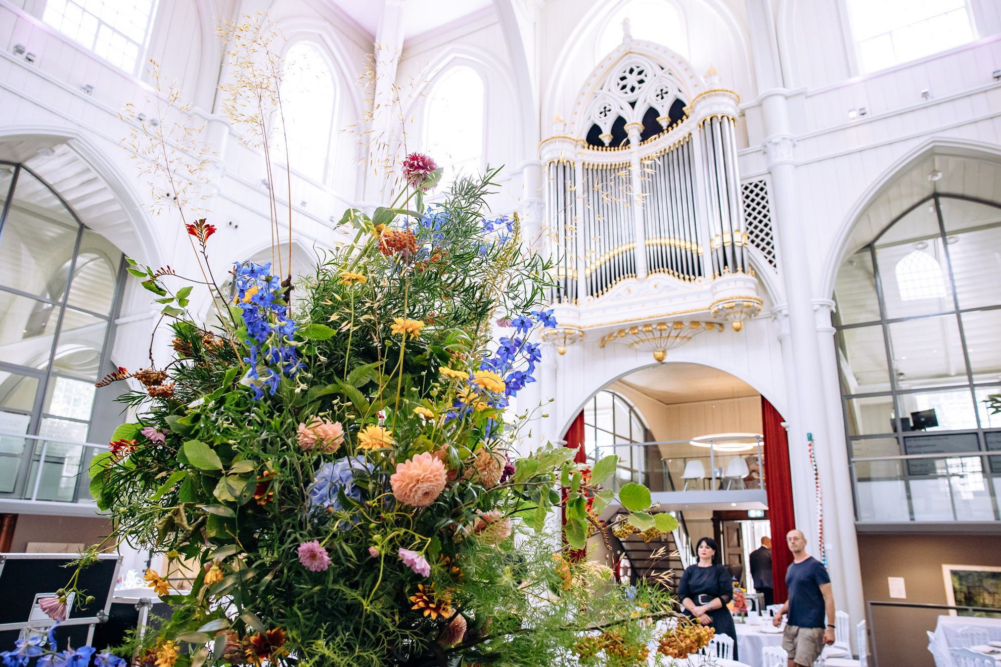 Amstelkerk: witte kerkzaal met orgel en een groot boeket veldbloemen
