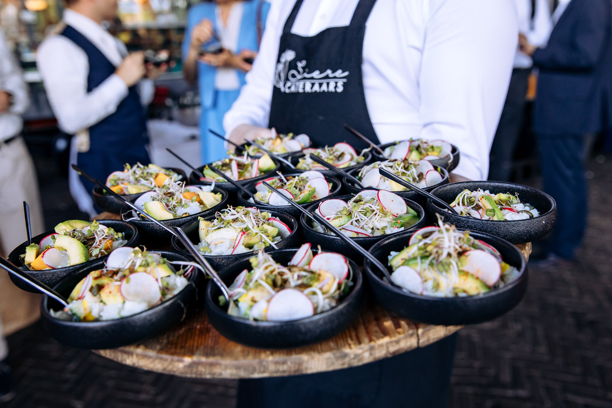 Siere Cateraars: rijstsalade in zwarte kommen op een houten dienblad