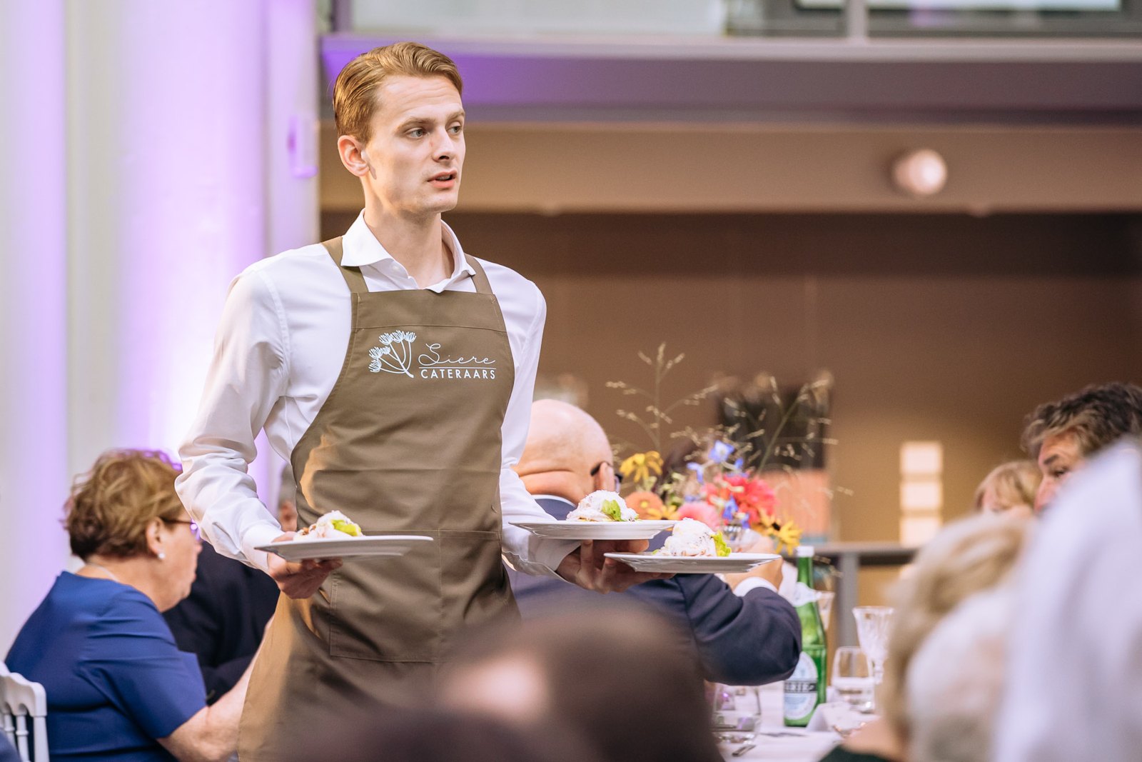 Bediening loopt met borden door de zaal