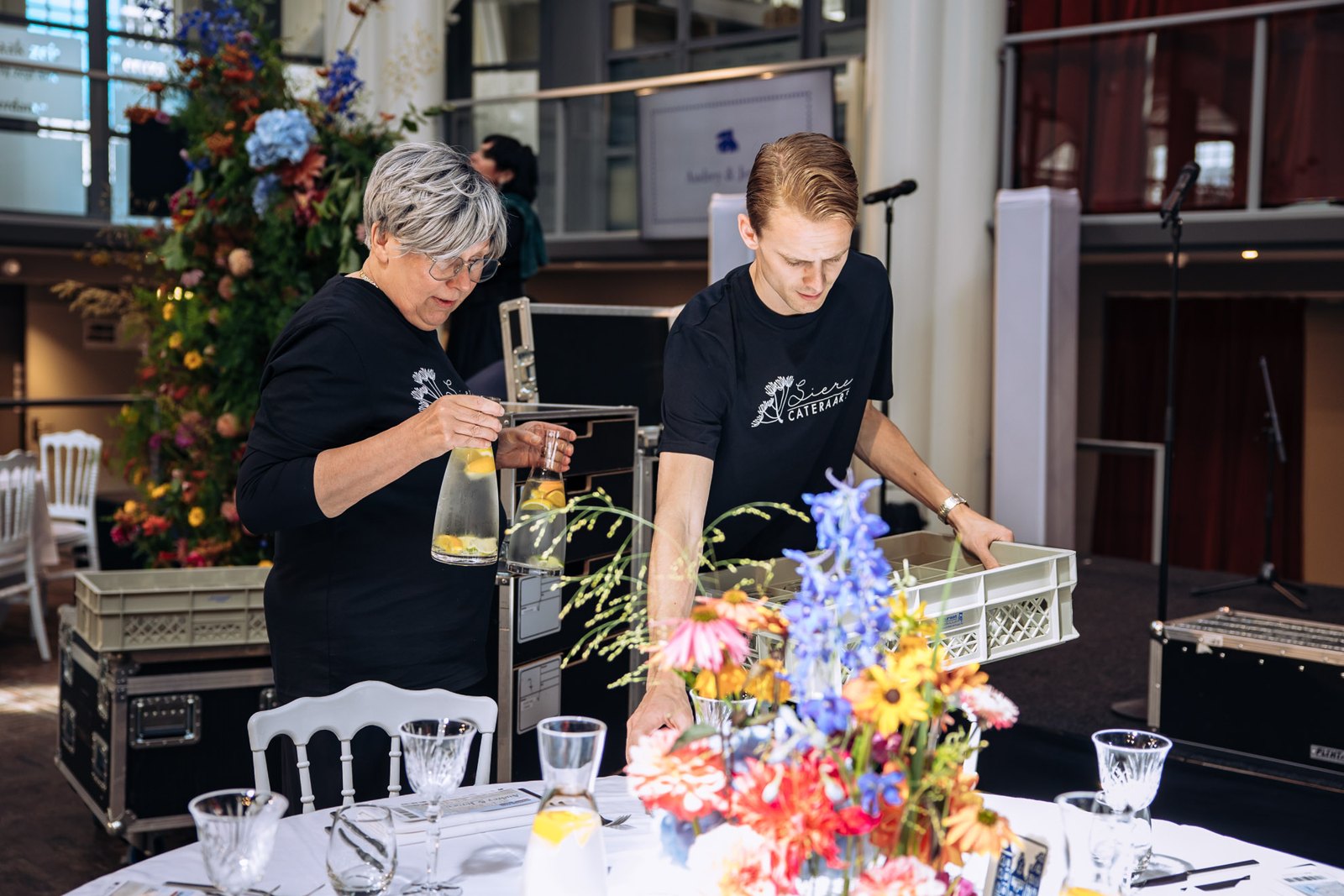 Berdien en een collega schenken in tussen de bloemen